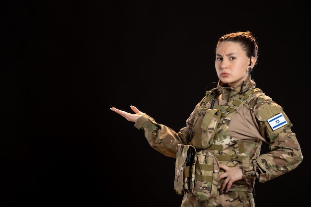 黒い壁に迷彩を着た女性兵士