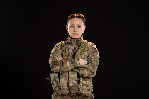 Female soldier iin camouflage on black wall