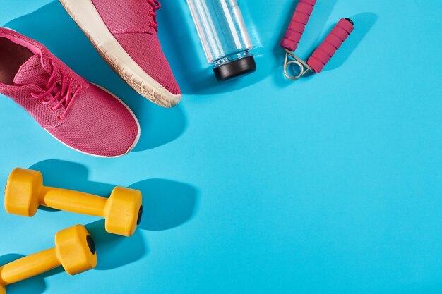 Female sport shoes and equipment on a bright blue background. Active lifestyle, body care concept. Top view. Copy space. Flat lay. Still life