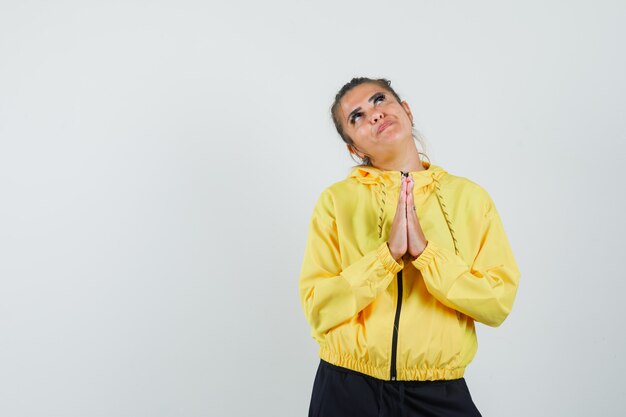 Female in sport suit showing namaste gesture and looking hopeful , front view.