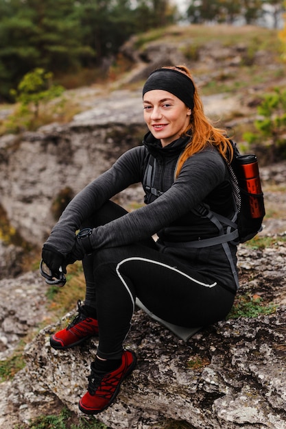 Foto gratuita pareggiatore sportivo femminile che si siede sulle rocce