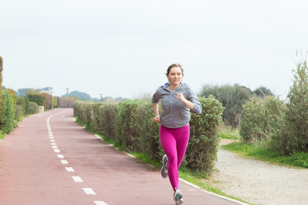 Female sprinter running fast on stadium track