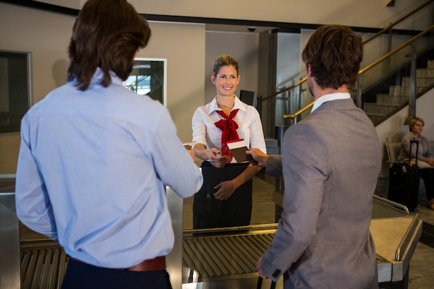 Female staff checking boarding pass of passengers at check-in counter