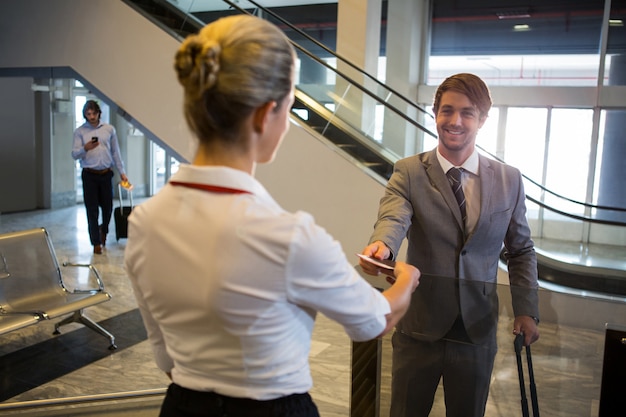 Free photo female staff checking boarding pass of passengers at check-in counter