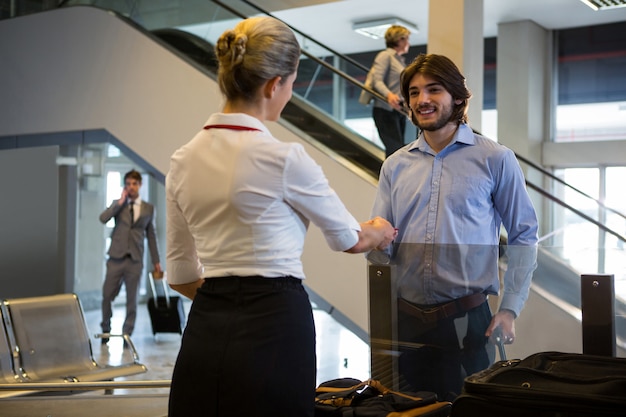 Free photo female staff checking boarding pass of passengers at check-in counter