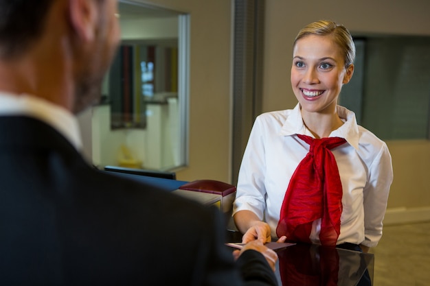 Free photo female staff giving boarding pass to the businessman