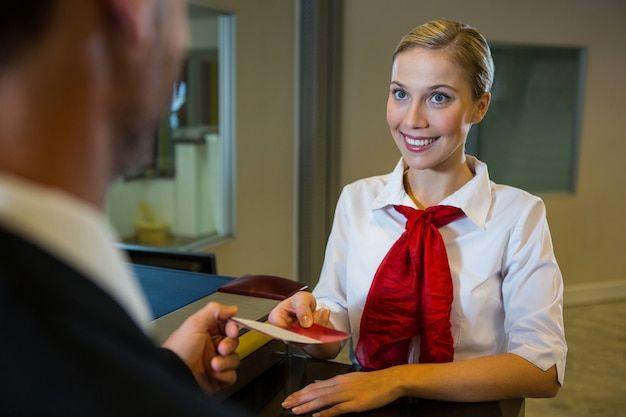 Free photo female staff giving boarding pass to the businessman