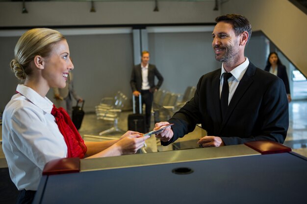 Female staff giving boarding pass to the businessman