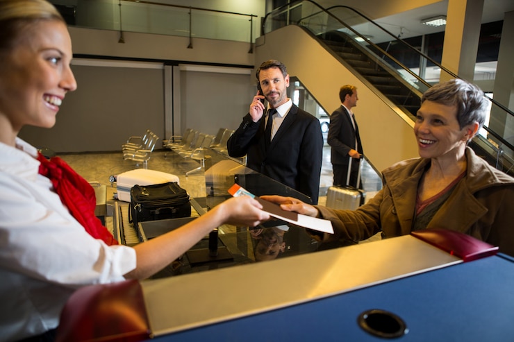 Free Photo female staff giving boarding pass to the passenger