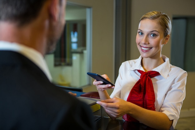 Personale femminile scansione carta d'imbarco con il telefono cellulare