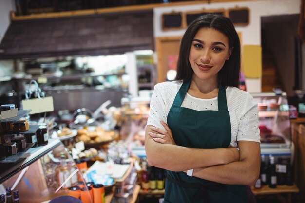 Female staff standing with arms crossed in super market