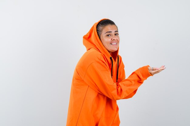 Female stretching hand in orange hoodie and looking needy