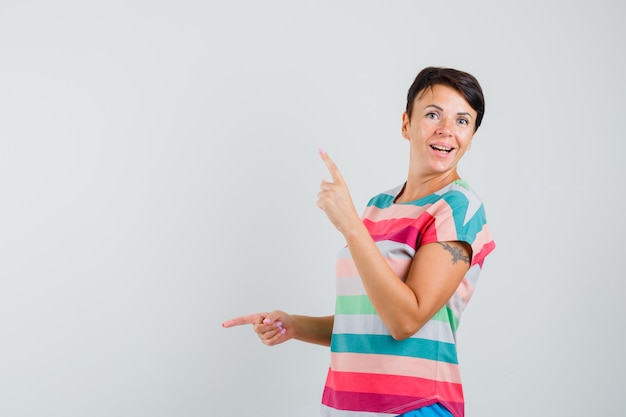 Female in striped t-shirt pointing fingers up and down and looking happy , front view.