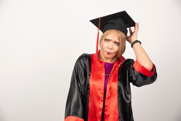 Female student in gown looking surprised on white.