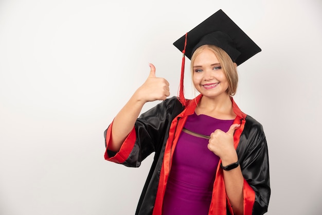 Studentessa in abito che fa i pollici su bianco.