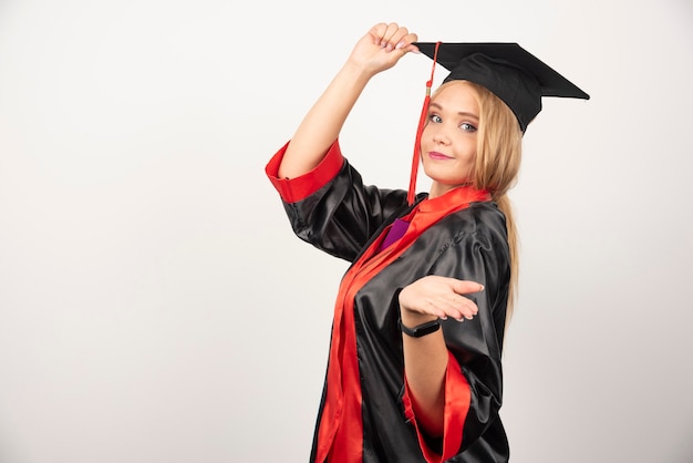 Female student in gown posing on white.