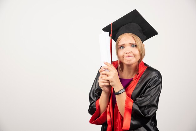 Female student in gown received diploma on white.