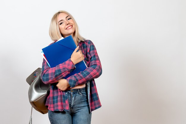 female student holding different files with smile on white