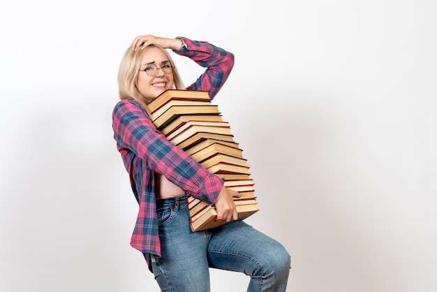 Free photo female student holding different heavy books on light-white