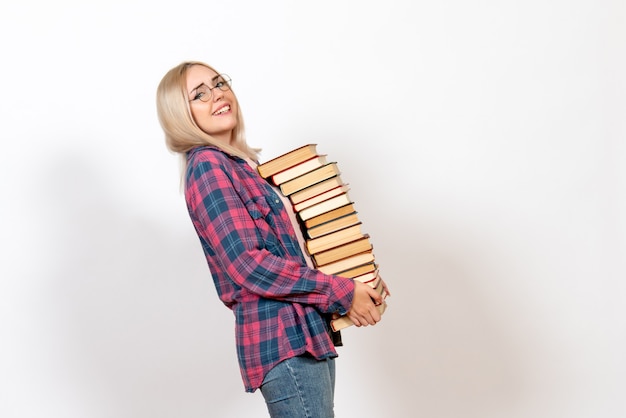 female student holding different heavy books on white