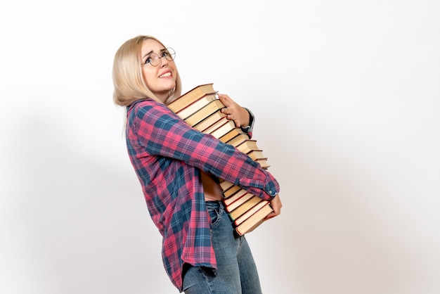 Free photo female student holding different heavy books on white