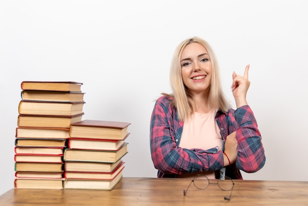 Studentessa appena seduta con libri sorridente su bianco