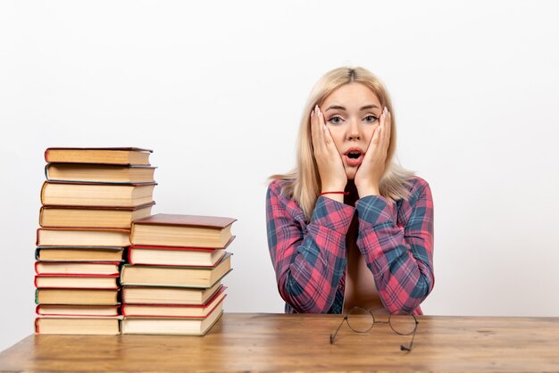 female student just sitting with books with surprised face on white