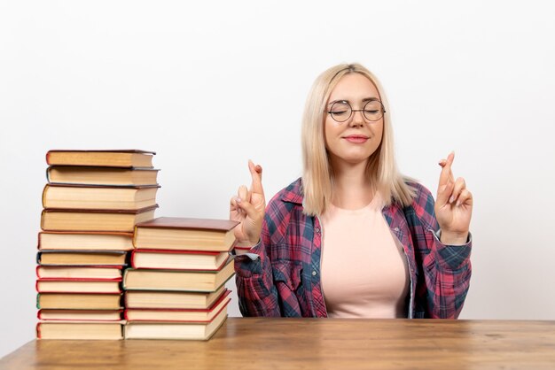 female student just sitting with different books crossing her fingers on white