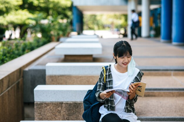 Female student sitting on the stairs and read a book.