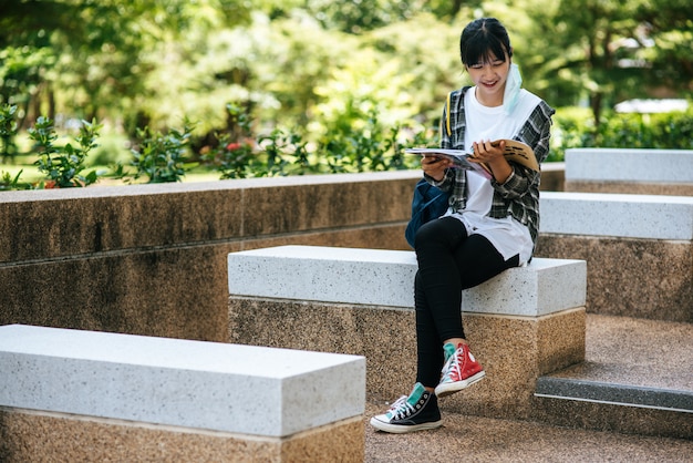 Female student sitting on the stairs and read a book.