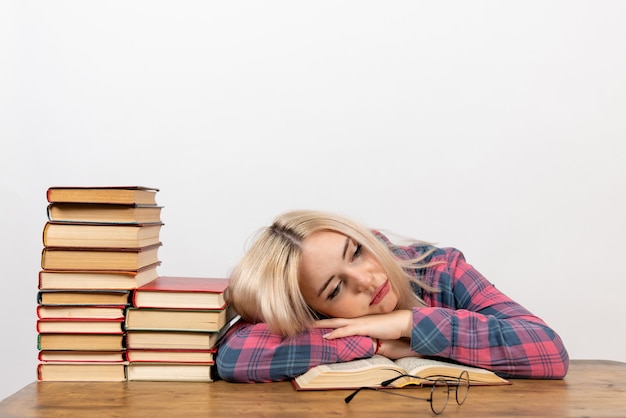 Studentessa seduta con i libri sensazione di stanchezza e dormire su bianco