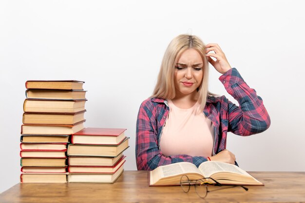 female student sitting with books and posing on white