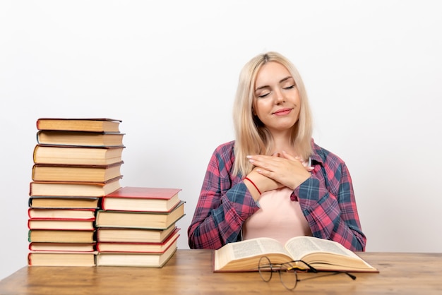 Studentessa seduta con libri e lettura su luce bianca