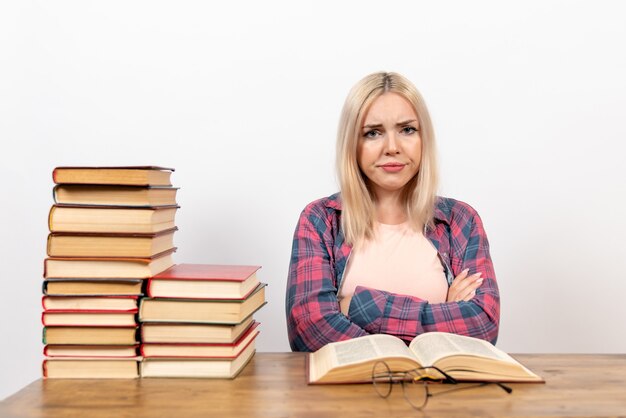 female student sitting with books and reading posing on white