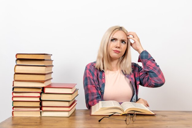 female student sitting with books and reading thinking on white