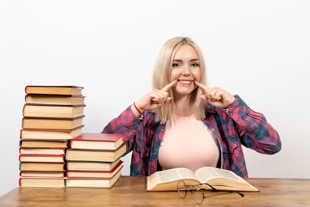 female student sitting with books and reading on white