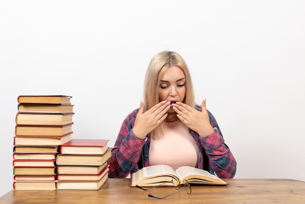 female student sitting with books and reading on white