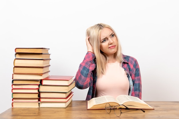 female student sitting with books and reading on white