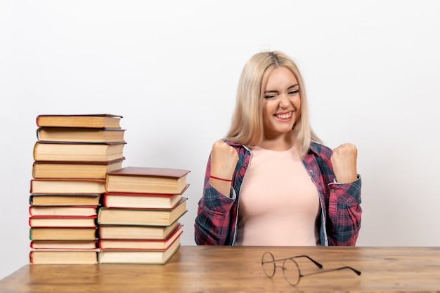 Studentessa seduta con libri e gioia su bianco