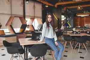 Free photo female student using laptop while sitting in cafe. concentrated young woman freelancer at work.