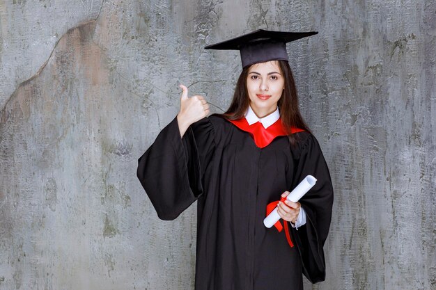 Female student wearing gown holding certificate graduating from college. High quality photo