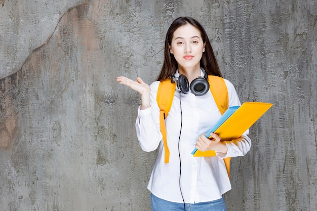 Female student with backpack and headphones holding open space. High quality photo