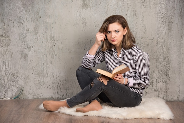 Studentessa con libro seduto in studio.