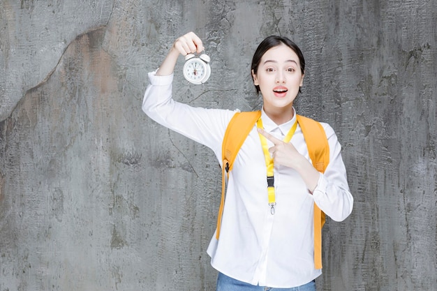 Studentessa con orologio giallo della holding dello zaino. foto di alta qualità