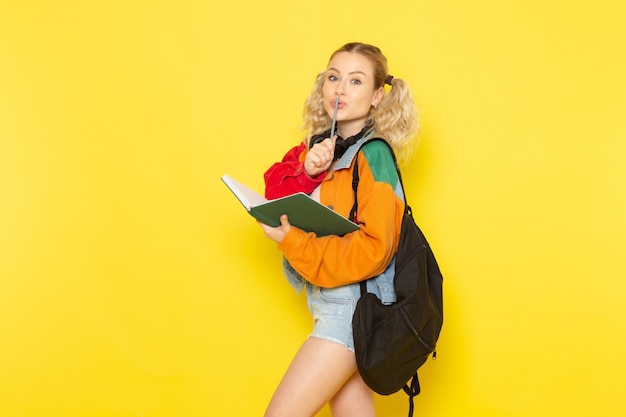 female student young in modern clothes holding copybook on yellow