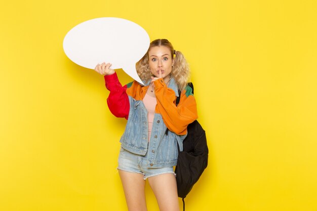 female student young in modern clothes holding a huge white sign on yellow