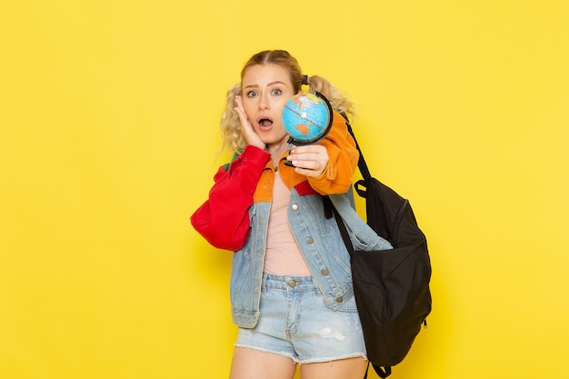 female student young in modern clothes holding little globe on yellow