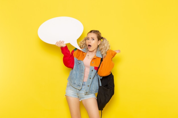 female student young in modern clothes holding white sign on yellow