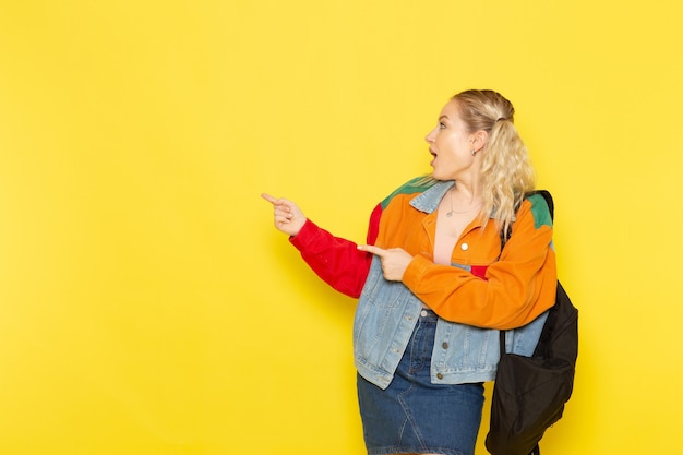 female student young in modern clothes just simply posing with smile on yellow