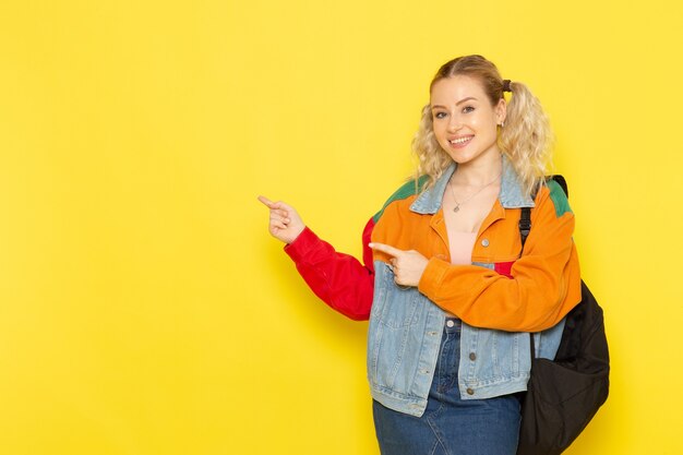 female student young in modern clothes just simply posing with smile on yellow